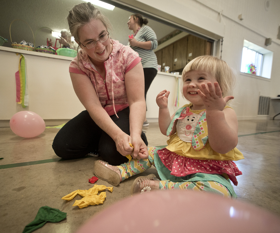 160326 WALBURG, TEXAS: 2-year-old Madeline De Reese of Jarrell, with her mom Kathleen De Reese, is feeling a lot of joy after popping a balloon during Saturday's Easter Egg Hunt celebration at St. Peter Lutheran Church in Walburg. After each year's Easter Egg Hunt, it's a tradition to go into the activity center and release even more energy by popping balloons before heading home. Popping balloons was something little Madeline really enjoyed a lot! Photo by Andy Sharp.