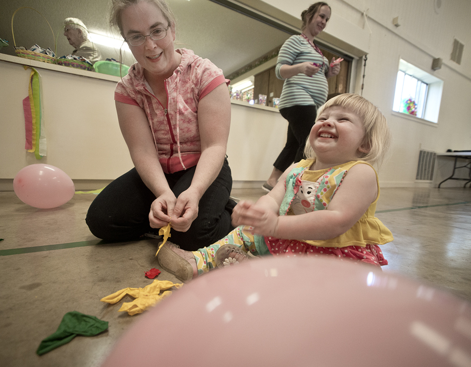 160326 WALBURG, TEXAS: 2-year-old Madeline De Reese of Jarrell, with her mom Kathleen De Reese, is feeling a lot of joy after popping a balloon during Saturday's Easter Egg Hunt celebration at St. Peter Lutheran Church in Walburg. After each year's Easter Egg Hunt, it's a tradition to go into the activity center and release even more energy by popping balloons before heading home. Popping balloons was something little Madeline really enjoyed a lot! Photo by Andy Sharp.